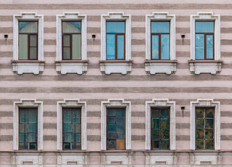 Many windows in a row on the facade of the urban historic apartment building front view, Saint Petersburg, Russia
