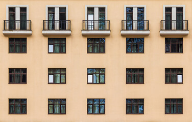 Fototapeta na wymiar Balconies and many windows in a row on the facade of the modern urban apartment building front view, Krasnaya Polyana, Sochi, Krasnodar Krai, Russia 