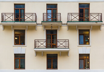 Several balconies and windows in a row on the facade of the modern urban apartment building front...