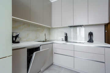Modern beige and gray stylish kitchen with a table, soft chairs, a sofa and a beige refrigerator....
