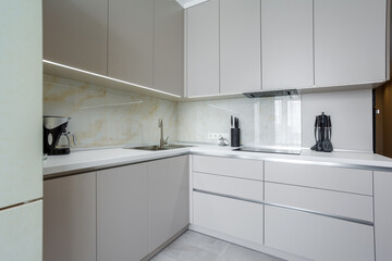 Fototapeta na wymiar Modern beige and gray stylish kitchen with a table, soft chairs, a sofa and a beige refrigerator. Floor tiles and laminate. Built in household appliance