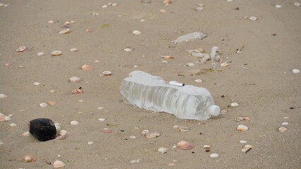 Plastic pollution. Empty plastic bottle on the beach. Pollution concept. Trash empty beverage packages thrown away