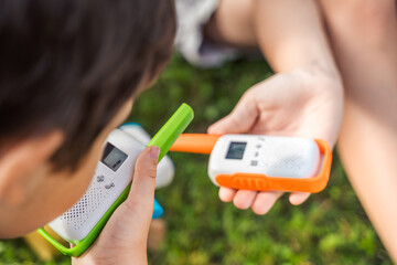 Small kids,girls play in walkie-talkie.Walkie Talkies with channels.Game of detectives, spies.Children talk,say messages at distance.Communication with parents in forest,park,hike.Finding lost people