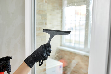 Professional Cleaning service company employee in rubber gloves remove dirt from windows using mop, close up