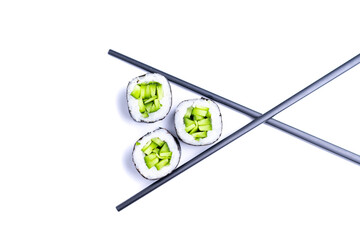 Two chopsticks holding fresh sushi roll isolated on white background