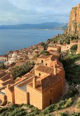Fototapeta na wymiar View of fortified medieval castle Monemvasia with Aegean sea and coast as background. Stone houses with dusty pink terracotta tiled roofs and blue sea.