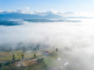 Mountain settlement in the Ukrainian Carpathians in the morning mist. Aerial drone view.