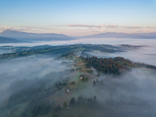 Flight over fog in Ukrainian Carpathians in summer. Mountains on the horizon. Aerial drone view.