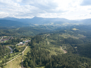 Green mountains of Ukrainian Carpathians in summer. Coniferous trees on the slopes. Aerial drone view.