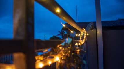 Fototapeta premium A string of lights hanging on a railing connected to a patio with dark blue skies 