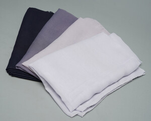 Stacks of nude colored veils neatly arranged on a gray background. Thin fabric blend of gray color that is ready to be used for Muslim women. Can also be used for sales displays. focus blur. hijab.