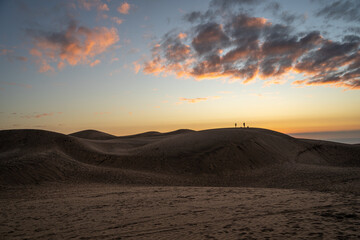 Fototapeta na wymiar Horizontal shot of colorful sunset on the dunes of Concón and silhouettes in the background, Chile