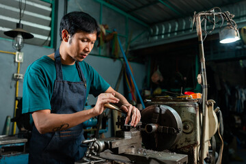 close-up, Asian technician Controlling small steel turning industrial tools, supervised by skilled technicians who stand behind the machine platform to supervise the steel turning process.