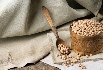 Chickpeas in a bowl with a spoon on a coarse cloth or burlap.