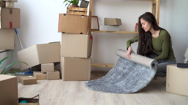 moving to a new home concept, young latin woman collects carpet and boxes for moving and relocation, renovation relocation process