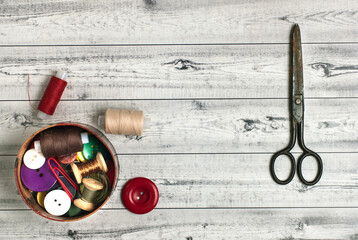 Sewing accessories on a gray table. Sewing threads, buttons and vintage scissors.