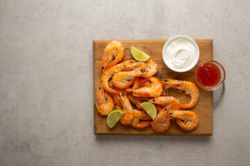 Top view shrimps on the board and lime wedges sauces copy space