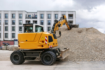 Excavator Scoops Rubble into Bucket. Wheeled Excavator Working on Construction Site. 