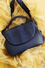 Women's handbag in blue on yellow textured background made of fabric.