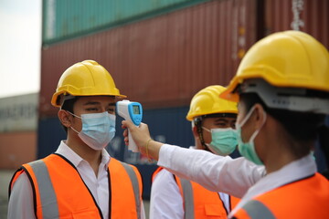 Factory workers with face masks protected against corona virus doing quality control of production in factory. People working during COVID-19 pandemic.