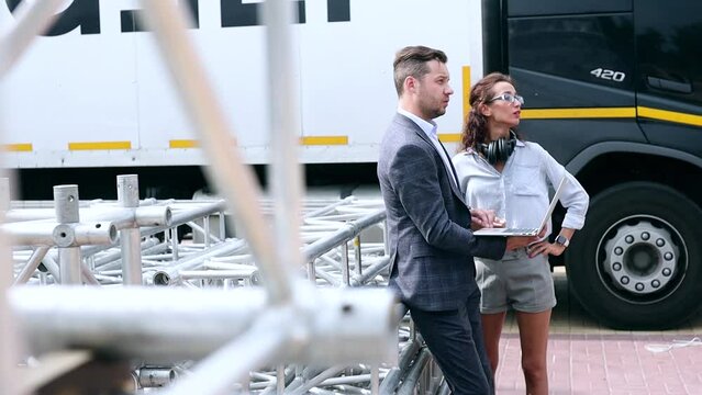 Logistics managers control the acceptance and shipment of goods. Installation of stage equipment and preparing for a live concert open air. Event manager portrait. Summer music city festival. Teamwork