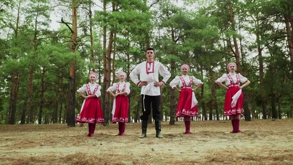 One man and four young women are dancing Russian Traditional dances in summer forest