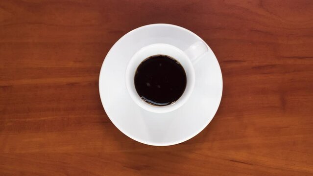 A cup of coffee on a brown table is filled with espresso stop motion animation.