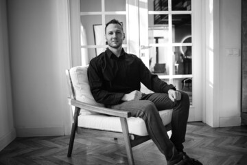 Black and white studio portrait of  elegant young handsome man in black shirt.