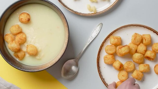 Vertical flat lay food video: the cook adds fried potato balls to the puree soup