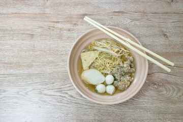 egg yellow noodles topping chop boiled pork and fish ball in soup on bowl