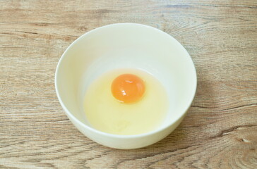 raw egg with yolk  in bowl on table