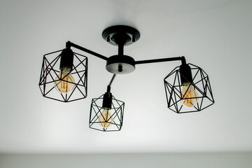 Geometric lamp hangs on a white ceiling. Modern, minimalist lamp that successfully complements the interior in loft style