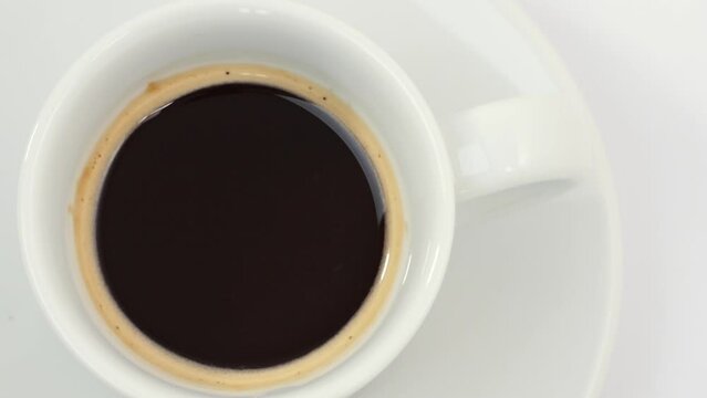 White coffe cup with hot espresso on a saucer spins, seamless looping.