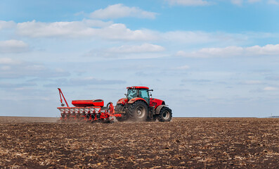 Spring sowing season. Farmer with a tractor sows corn seeds on his field. Planting corn with...