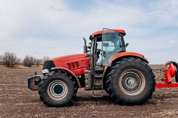 Spring sowing season. Farmer with a tractor sows corn seeds on his field. Planting corn with trailed planter. Farming seeding. The concept of agriculture and agricultural machinery.