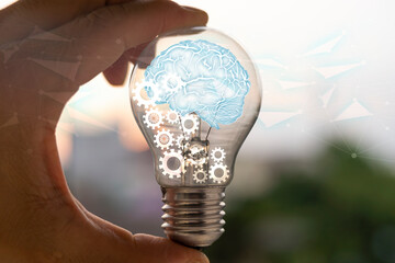 Light bulb with brain inside the hands of the businessman.