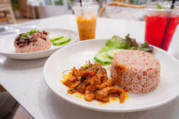 ( Panang ) Red spicy curry with pork and coconut milk eat with rice on white plate. Thai style food cooked to order in restaurant background.
