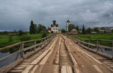 The bridge over the Ken River and Pyatnitskaya Church. Arkhangelsk region. Russia