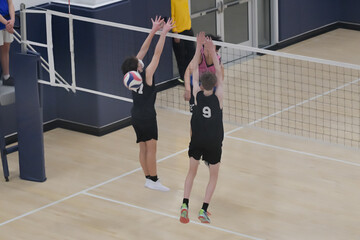 Male volleyball player hits the ball through the block