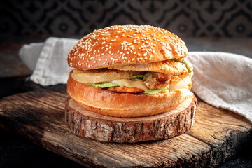 Plump burger with chicken breast, pineapple, cheese, lettuce and sauce on a wooden board....