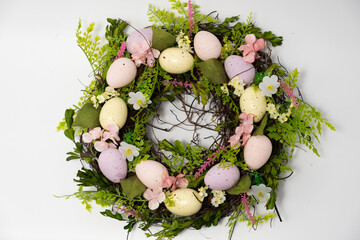 three blue spotted chicken eggs and a wreath of willow twigs on a white background, top view