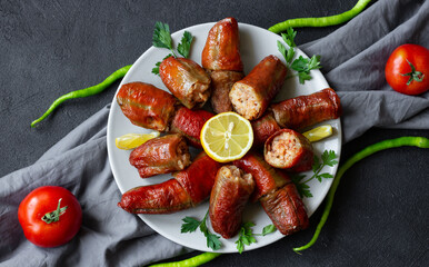 Stuffed dried peppers cooked in pot in plate on black rustic background