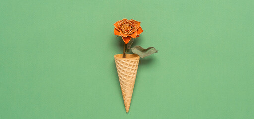 Dried rose in a waffle cone on a green background. Top view, flat lay, banner. Creative layout.