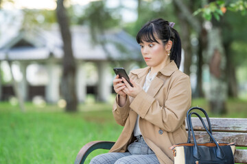 スマホ画面を見て驚く女性