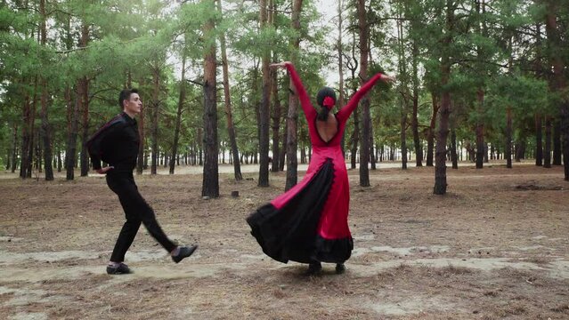 Elegant and graceful asian woman and caucasian man are dancing Traditional Spanish dance in summer forest