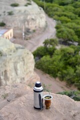 equipo de mate argentino, termo de acero y copa de porongo, compartiendo al aire libre sobre una...