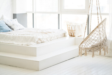 Bed with white linens in a bright bedroom with a large window