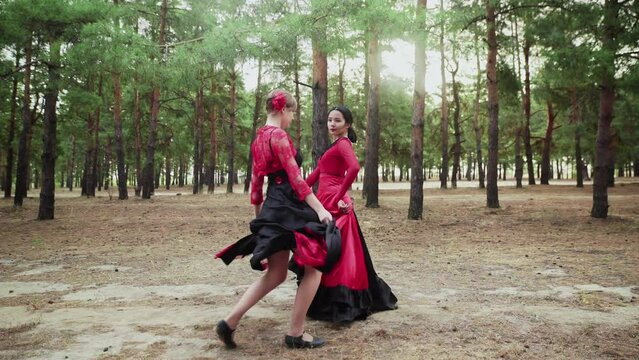 Elegant and graceful asian and caucasian women are dancing Traditional Spanish dance in summer forest