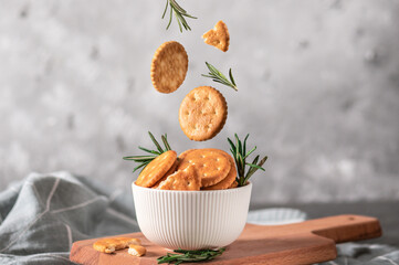 Levitation of salted crackers with rosemary on light background