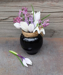 Bouquet of spring flowers (Crocuses, Scilla, Corydalis) in a ceramic small vase, spring festive composition, selective focus, vertical orientation.